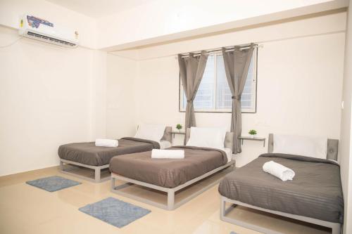 a room with three beds and a window at Z Express Zen Elite in Pune