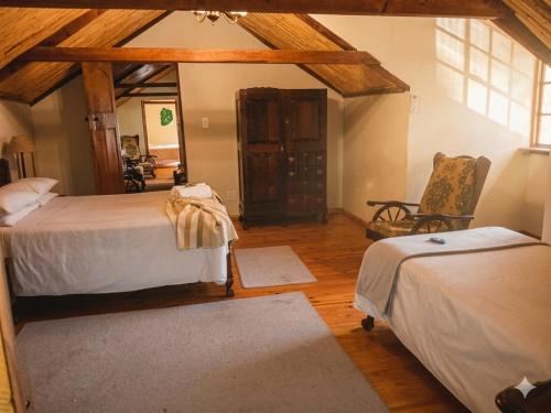 a bedroom with two beds and a chair in a room at Route 62 B&B in Robertson