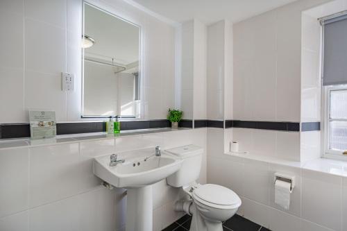 a white bathroom with a toilet and a sink at The Crown Hotel, Boroughbridge, North Yorkshire - The Coaching Inn Group in Boroughbridge
