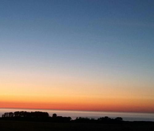 a blue and orange sky at sunset with trees at Ferienwohnung und Ferienzimmer in Neubukow