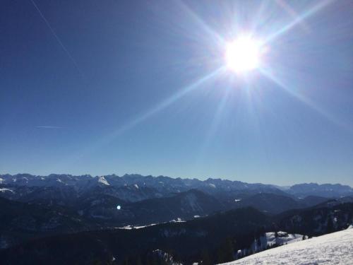 eine Sonne scheint auf einen schneebedeckten Berg in der Unterkunft Bocksleitnerhof in Wackersberg
