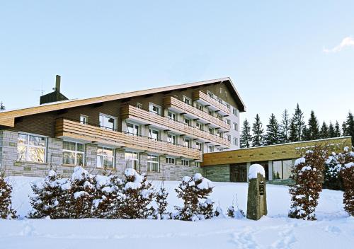 a large building with snow in front of it at Hotel Srní a Depandance in Srní