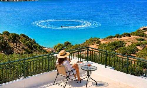 a woman sitting in a chair on a balcony looking at the ocean at Istron Homes in Istro