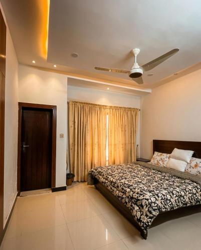 a bedroom with a bed and a ceiling fan at Ranim Family Lodge - Abbottabad in Abbottabad