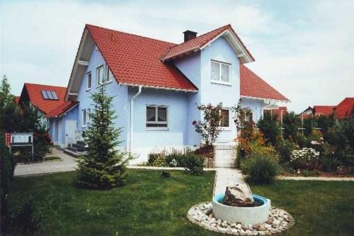 a white house with a red roof in a yard at Gästehaus Schwien in Rust