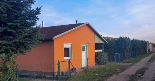 a small orange and orange house next to a fence at kleines Ferienhaus am Feldrand in Malchow