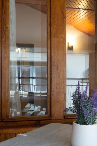 a vase with purple flowers in front of a window at Valchevi Apartments in Chernomorets
