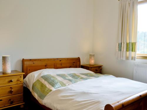 a bedroom with a bed and a dresser and a window at Blythswood in Glenfinnan