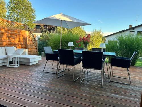 a patio with a table and chairs and an umbrella at Tu Casa Chiemsee Ferienhaus in Gstadt am Chiemsee