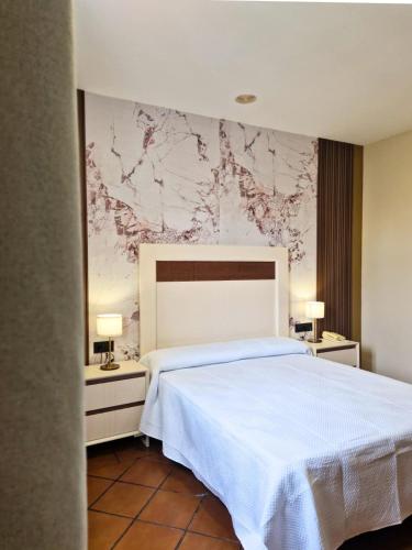 ein Schlafzimmer mit einem weißen Bett und einer Marmorwand in der Unterkunft Los Bronces in Lucena