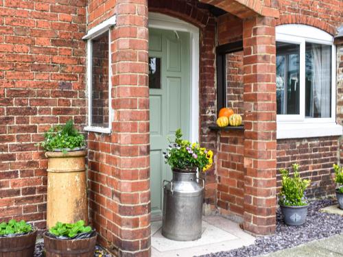 a brick house with a green door and potted plants at Brynfields in Ashbourne