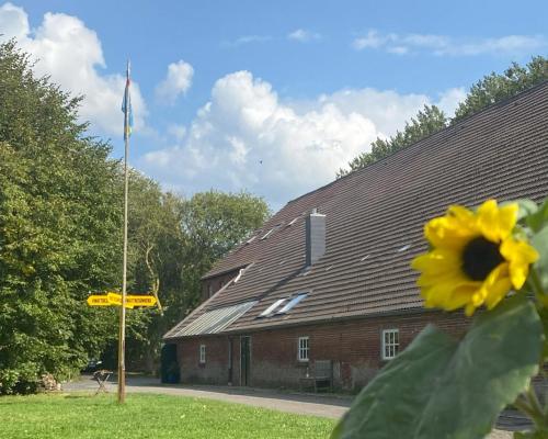a building with a flag and a yellow flower at Gulfhof Friedrichsgroden in Carolinensiel