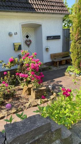 a garden with pink flowers and a bench in front of a house at Ferienwohnung in Hannoversch Münden
