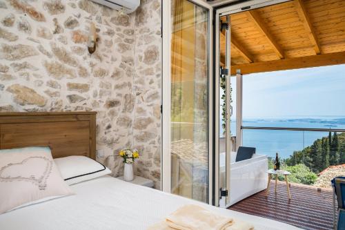 a bedroom with a view of a stone wall at Art House with Seaview & Jacuzzi by Konnect in Spartýlas