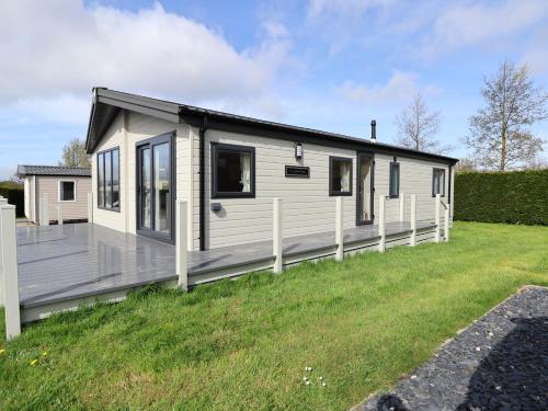 a white house with a deck on a grass field at White House in St Asaph