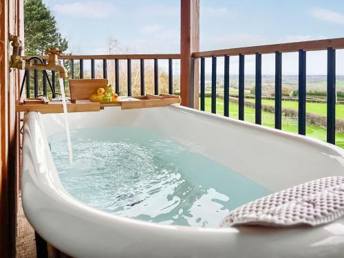 a bath tub on a balcony with a view of the ocean at The Rabbit Hole - Uk50123 in Bodelwyddan