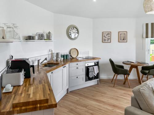 a kitchen with white cabinets and a table with chairs at The Rabbit Hole - Uk50123 in Bodelwyddan