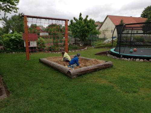 two children playing in a sandbox in a park at Bungalow Hartmann in Lüssow