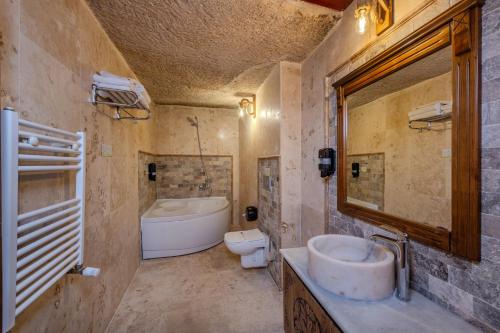 a bathroom with a sink and a tub and a toilet at Stone House Cave Hotel in Göreme