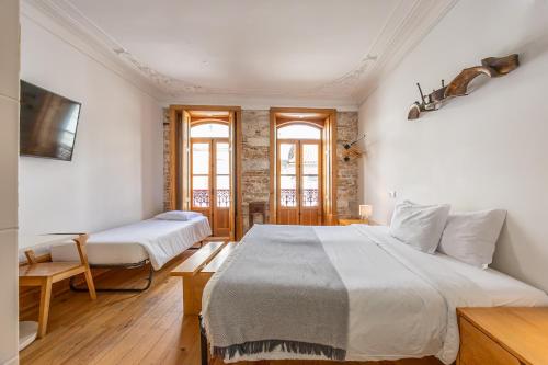 a bedroom with two beds and two windows at Casa da Baixa by PURUS in Coimbra