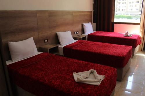 a hotel room with two beds with red sheets at فندق النادي in Aswan