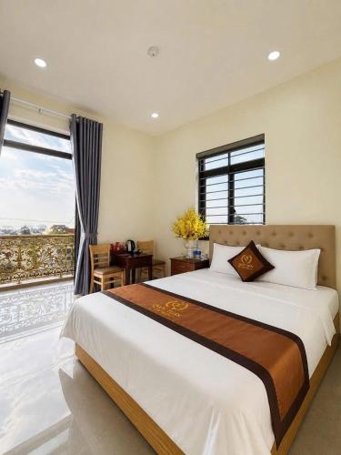 a bedroom with a large bed and a desk and window at Hotel QUỐC TUẤN in Ban Ay Dlă (2)