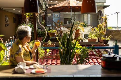 a woman sitting at a table with a glass at Studio Bangalô Belém Hospedagem in Belém