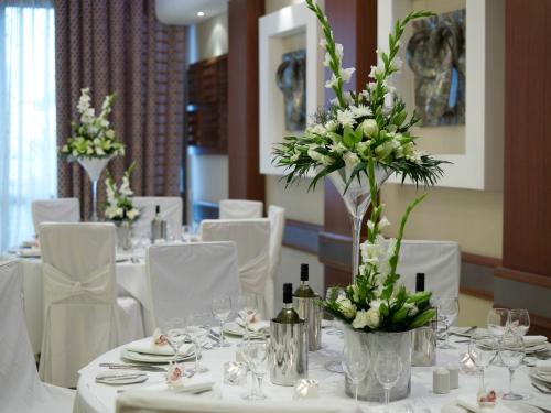 a dining room with white tables and white flowers at Atlantica Miramare Beach in Limassol