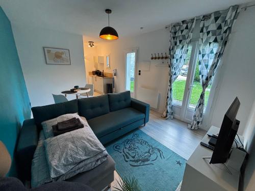 ein Wohnzimmer mit einer blauen Couch und einem Fernseher in der Unterkunft Maisonnette de Senlis in Senlis