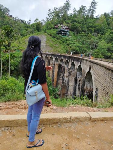 a woman standing in front of a bridge at Secret Garden Ella Cabana & Stay in Ella