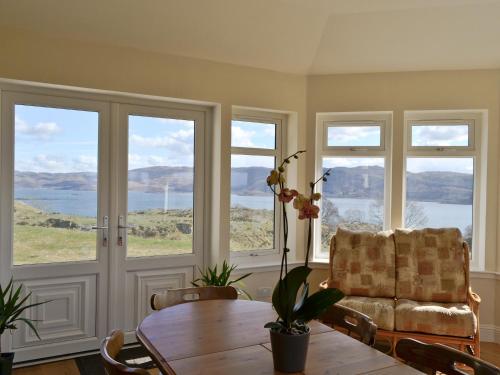 a living room with a table and a couch and windows at Degnish Farmhouse - Swwu in Kilmelfort