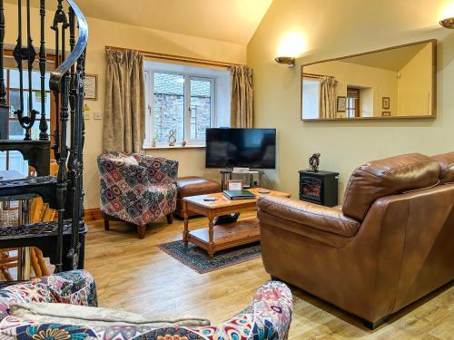 a living room with a leather couch and a television at Ploughman's Rest - Uk51336 in Peebles