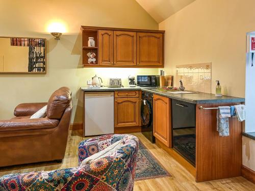 a kitchen with wooden cabinets and a couch in a room at Ploughman's Rest - Uk51336 in Peebles