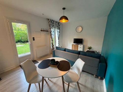 ein Wohnzimmer mit Sofa, Tisch und Stühlen in der Unterkunft Maisonnette de Senlis in Senlis
