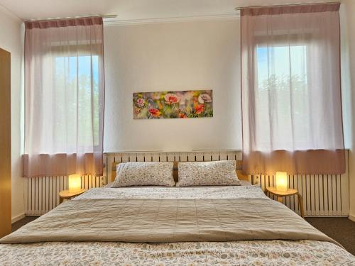 a bedroom with a bed and two windows at Ferienhof Dahl in Wurster Nordseeküste