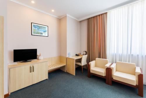 a room with a television and two chairs and a desk at Cruise Hotel in Tbilisi City