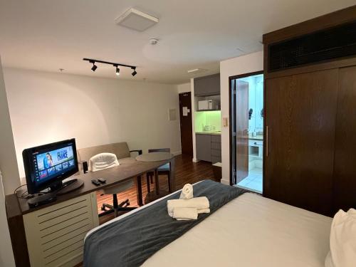 a bedroom with a bed with a television and a living room at Hotel Alameda Campinas Paulista in São Paulo