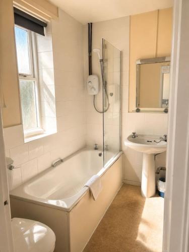 a white bathroom with a tub and a sink at The Dolphin Hotel in Wincanton