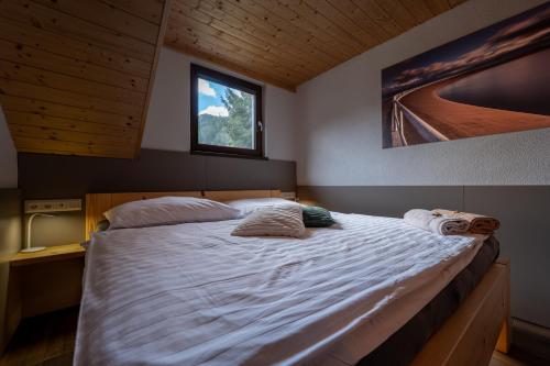 a bedroom with a large bed with white sheets and a window at Chalet Dereše in Liptovský Mikuláš
