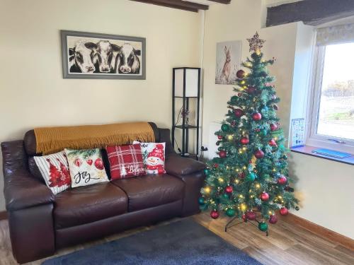 a living room with a christmas tree and a leather couch at Teifi Cottage - Uk49590 in Llansawel