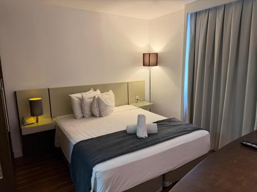 a hotel room with a bed with two towels on it at Hotel Alameda Campinas Paulista in São Paulo