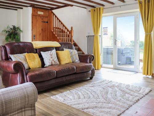 a brown leather couch in a living room with yellow curtains at Cothi Cottage - Uk49588 in Llansawel
