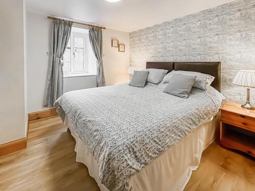 a bedroom with a large bed and a brick wall at Cosy Neuk - Uk51345 in Peebles