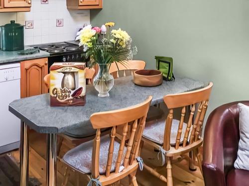 a kitchen with a table with chairs and flowers on it at Cosy Neuk - Uk51345 in Peebles