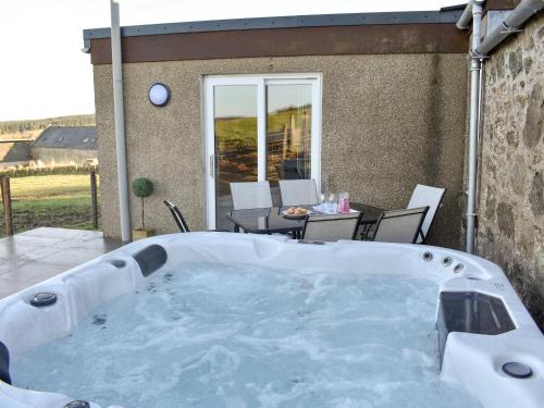a hot tub in a yard with a table and chairs at Benwells Holiday Cottage in Maud
