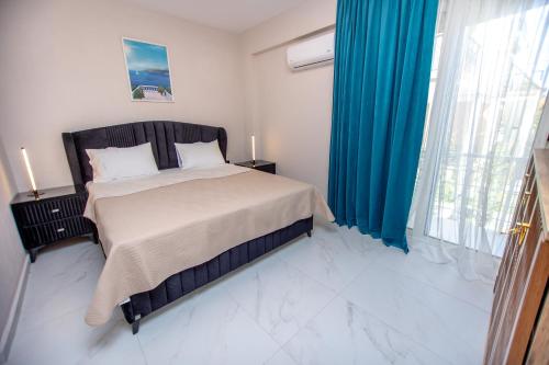 a bedroom with a large bed with blue curtains at Veranda White in Nea Vrasna