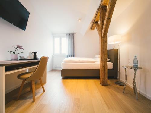 a bedroom with a bed and a desk with a chair at Landhotel Adler in Sigmarszell