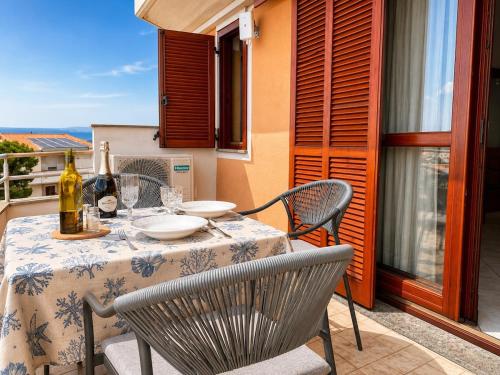 a table with chairs and a bottle of wine on a balcony at Luna House - Key to Villas in Valledoria