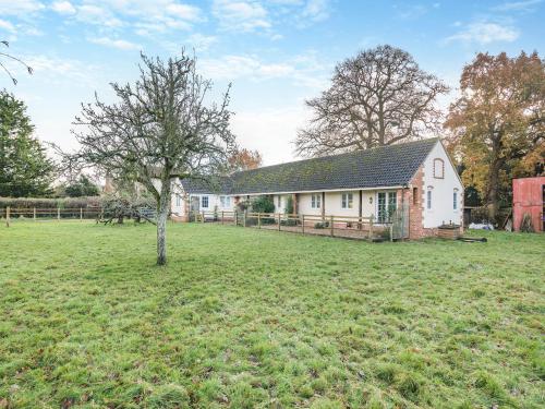 a house with a tree in the middle of a field at Paddock Barn in North Nibley