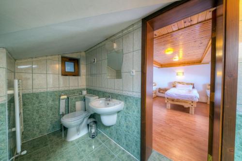 a bathroom with a sink and a toilet and a bed at Rhodope House Momchil Yunak in Momchilovtsi